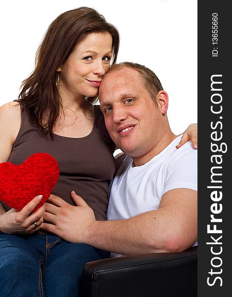 Young couple sitting in a chair holding a heart. Young couple sitting in a chair holding a heart.