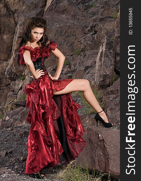 Pretty female model in red on the rocks background. Pretty female model in red on the rocks background