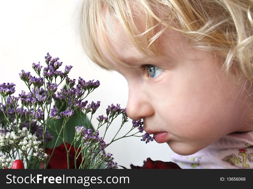 The little blond girl smelling bouquet of flowers. The little blond girl smelling bouquet of flowers