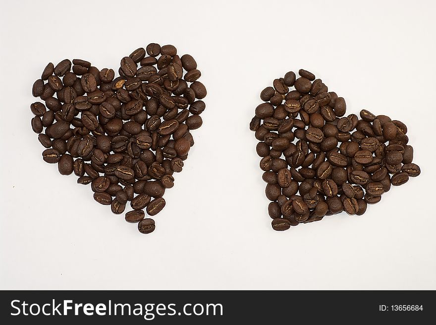 Fresh coffee beans in a shape of two hearts.