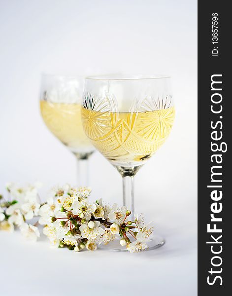 Wine glasses with white wine and a plums branch