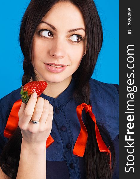 Beautiful lady holding a strawberry, studio shot on blue background