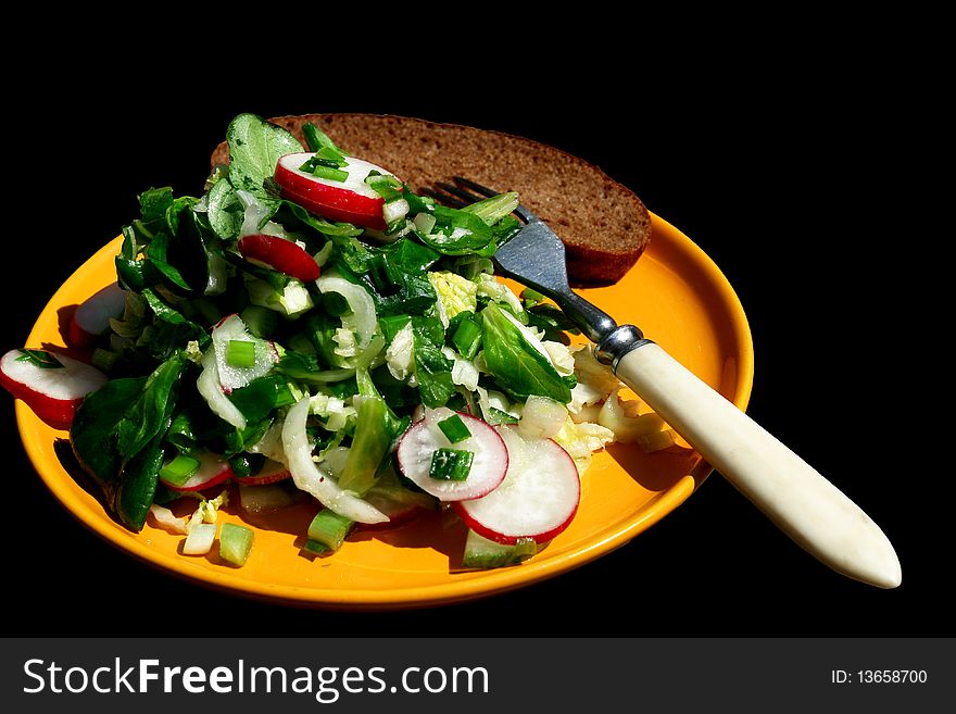 Salad in a yellow plate on a black background
