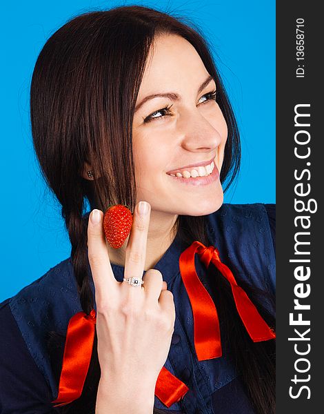 Beautiful lady holding a strawberry, studio shot on blue background