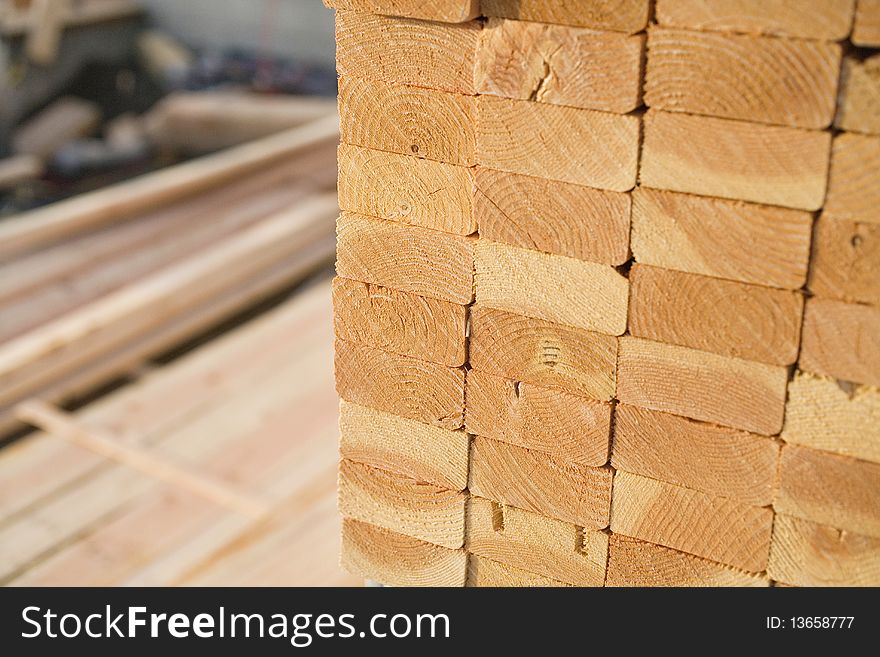 Selective focus image of stacks of 2x4 boards at a construction site, with more lumber visible in the background. Horizontal shot. Selective focus image of stacks of 2x4 boards at a construction site, with more lumber visible in the background. Horizontal shot.