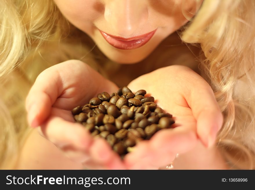 Beautiful girl with long blonde hair holding in hands coffee beans