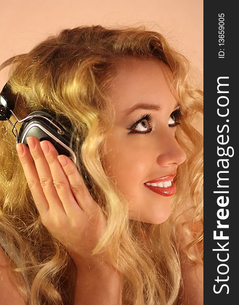 Beautiful girl with long blonde hair in headphones listening to music. Beautiful girl with long blonde hair in headphones listening to music