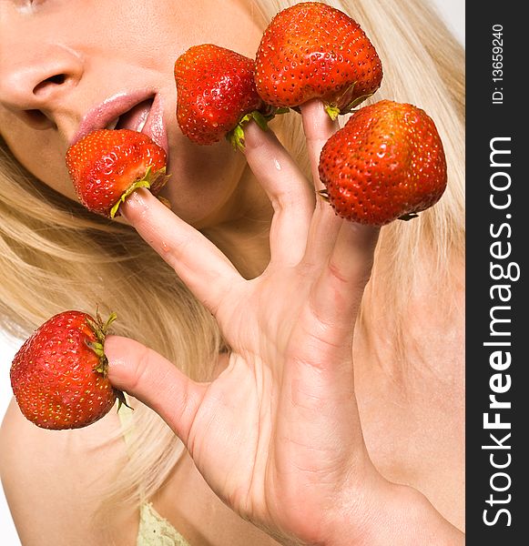 Sweet caucasian girl eating strawberries picked on fingertips