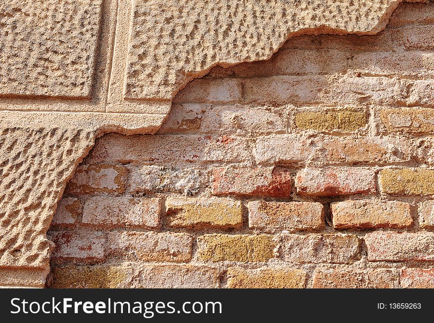 Partly covered old brick wall with some of the decorative cementwork still showing.