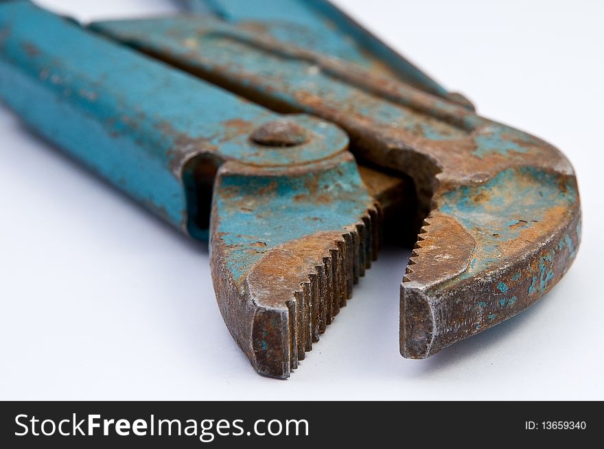 Old green and rusty pipe tongs on white underground