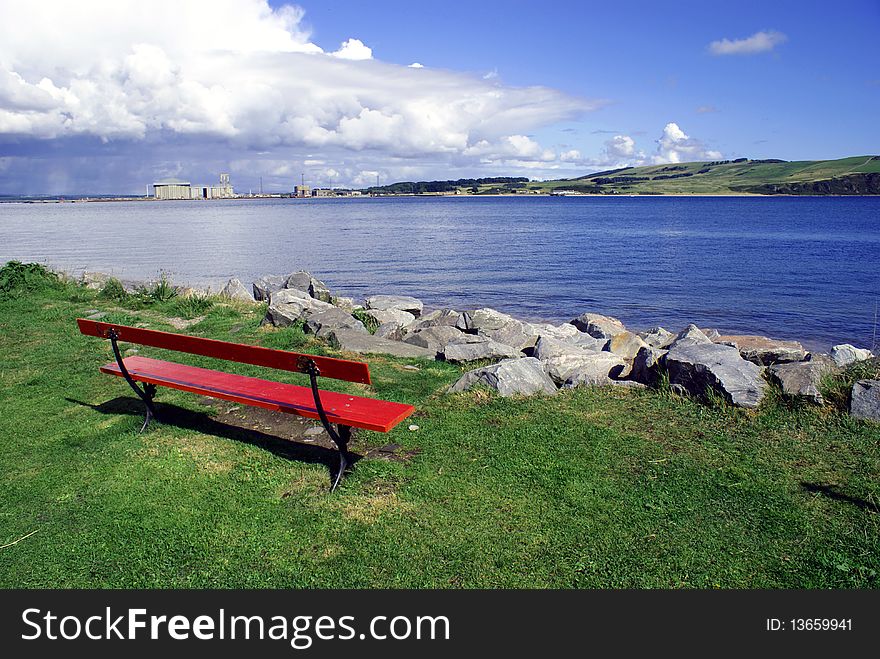 A red bench facing a calm coastal view.