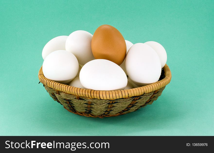 Eggs in wicker basket against green background