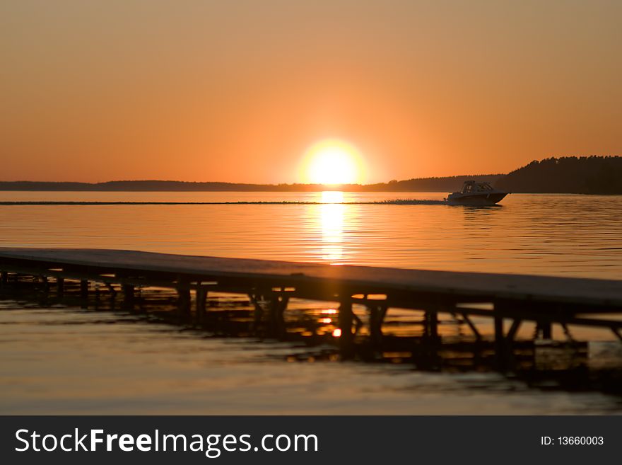 Sunset over Volga river, wooden quay at foreground and boat. Sunset over Volga river, wooden quay at foreground and boat