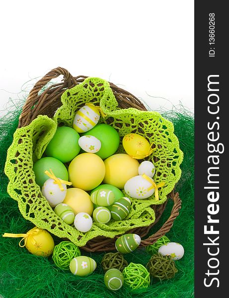 Colorful painted Easter eggs in the basket on green grass isolated on white background