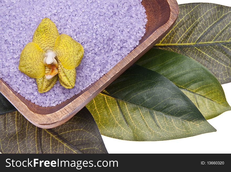 Orchid in a bowl of purple bath salts isolated on a leaf background. Orchid in a bowl of purple bath salts isolated on a leaf background.