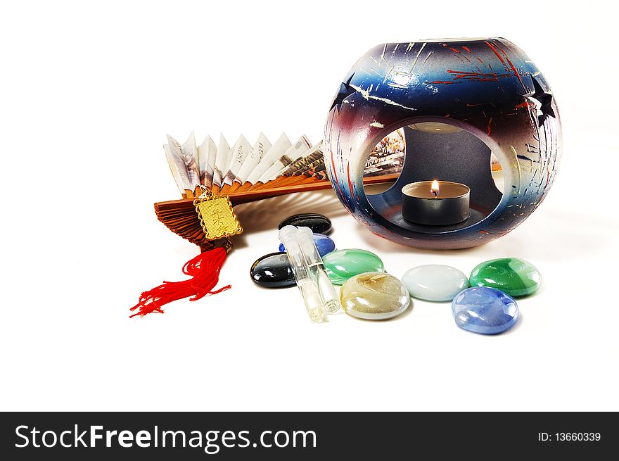 Oil burner with a candle, fan, oil, stones on a white background. Oil burner with a candle, fan, oil, stones on a white background