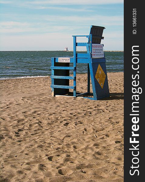 Lifeguard chair on a beach with view of lighthouse in the distance. Lifeguard chair on a beach with view of lighthouse in the distance