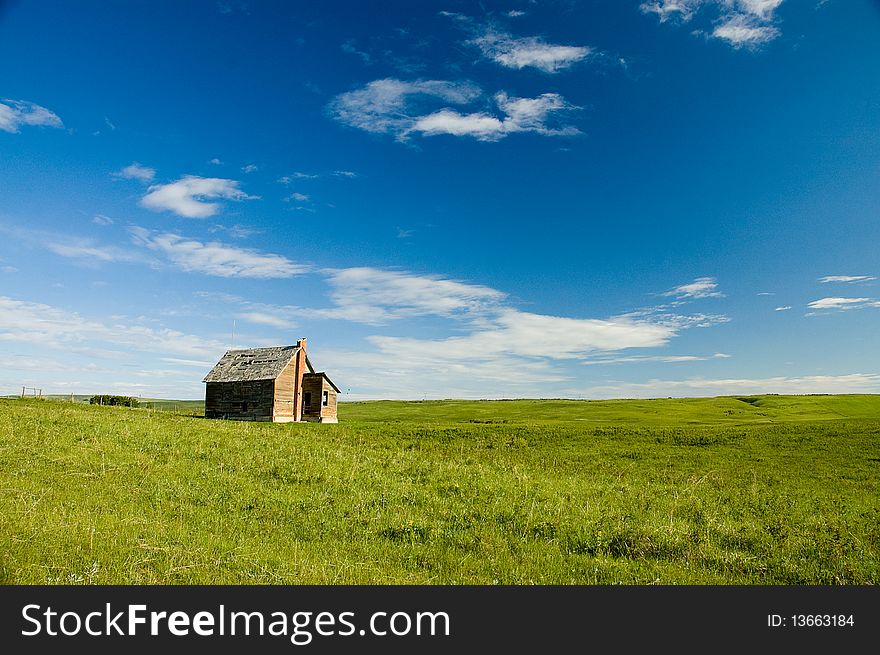 Wood building with brick chimney in green pasture against blue sky with some cloud. Wood building with brick chimney in green pasture against blue sky with some cloud.