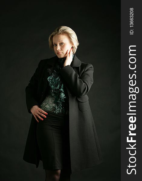 Portrait of the beautiful, young girl-blonde in a green transparent blouse and a black coat. Portrait of the beautiful, young girl-blonde in a green transparent blouse and a black coat