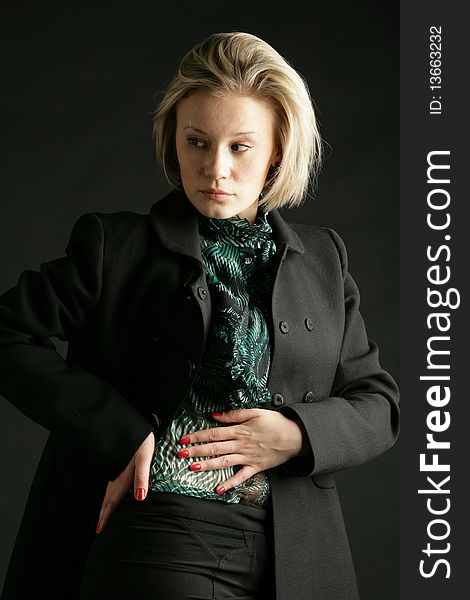 Portrait of the beautiful, young girl-blonde in a green transparent blouse and a black coat. Portrait of the beautiful, young girl-blonde in a green transparent blouse and a black coat