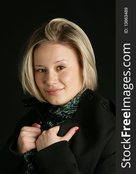 Portrait of the beautiful, young girl-blonde in a green transparent blouse and a black coat. Portrait of the beautiful, young girl-blonde in a green transparent blouse and a black coat