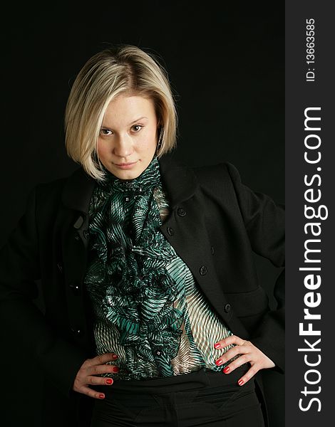 Portrait of the beautiful, young girl-blonde in a green transparent blouse and a black coat. Portrait of the beautiful, young girl-blonde in a green transparent blouse and a black coat