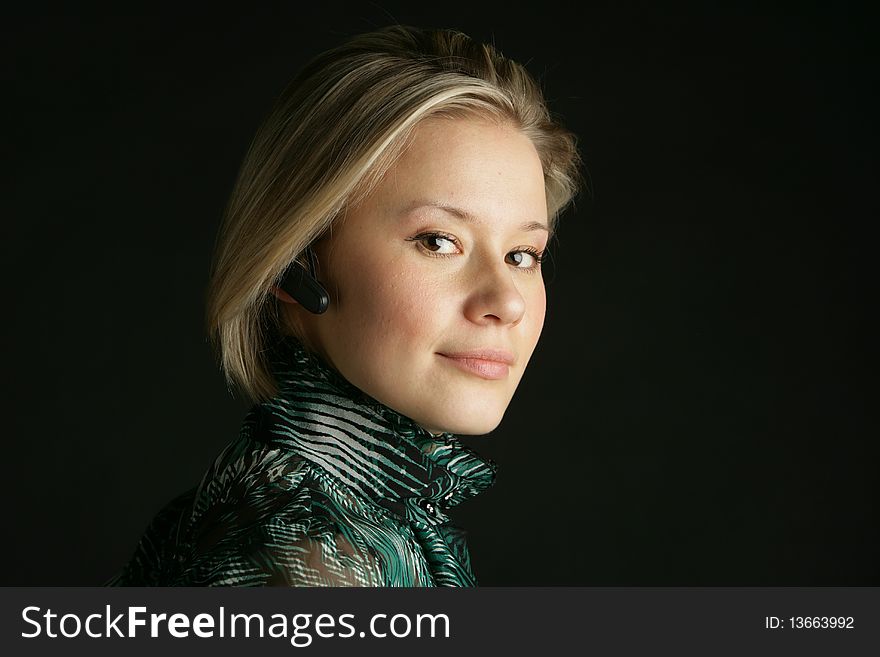 Portrait of the beautiful, young girl-blonde in a green transparent blouse and with hands-free. Portrait of the beautiful, young girl-blonde in a green transparent blouse and with hands-free