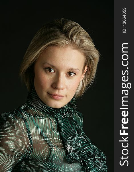 Portrait of the beautiful, young girl-blonde in a green transparent blouse. Portrait of the beautiful, young girl-blonde in a green transparent blouse