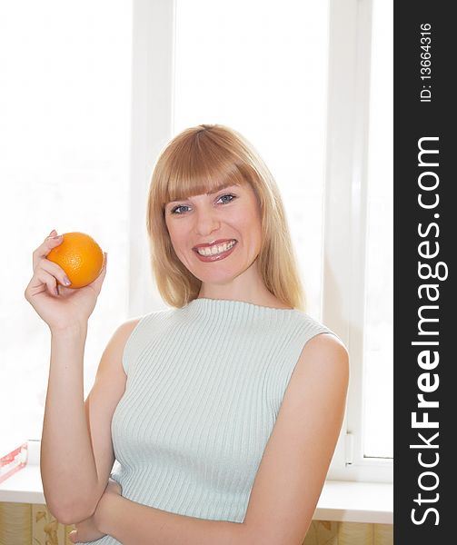 The young woman with an orange in a hand on a background
