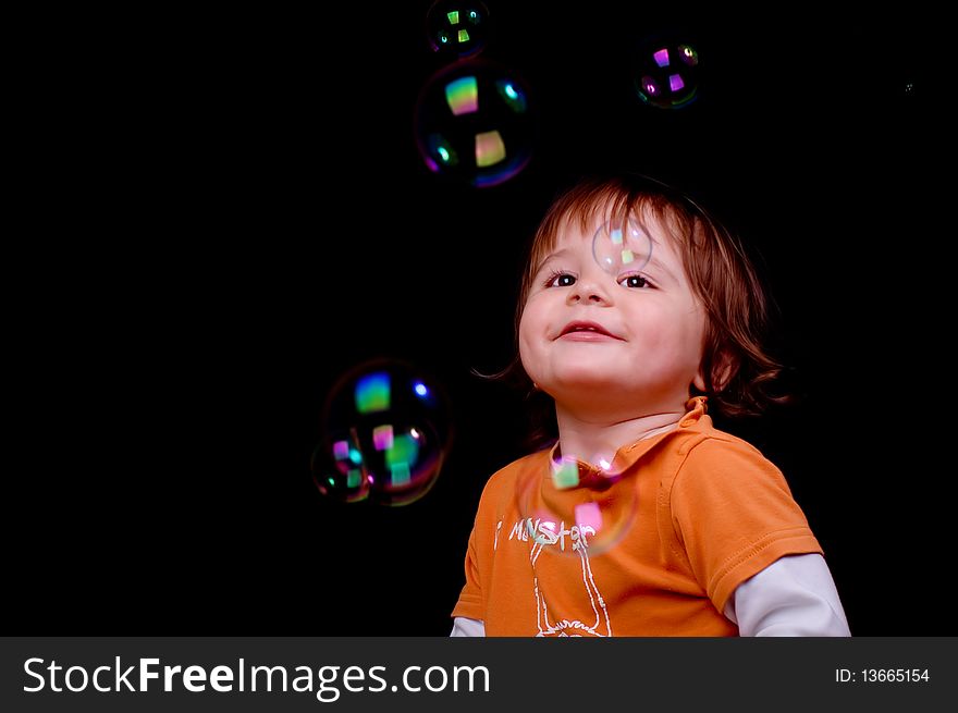 Little boy looking at soap bubbles on black background. Little boy looking at soap bubbles on black background