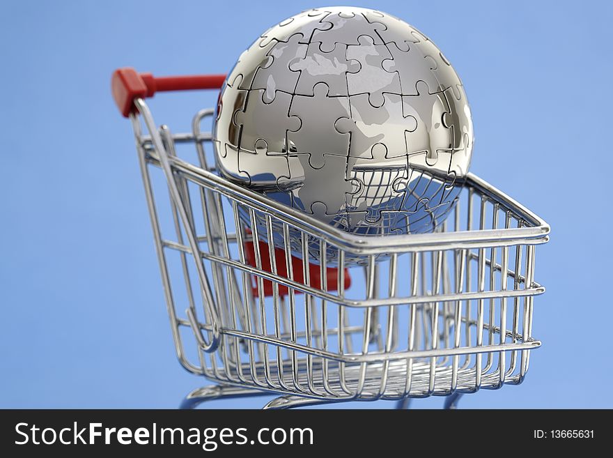 Metal puzzle globe with shopping cart on blue background