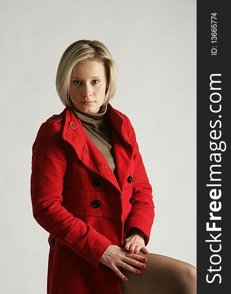 The beautiful young girl-blonde dressed in a brown dress and a red coat. The beautiful young girl-blonde dressed in a brown dress and a red coat.