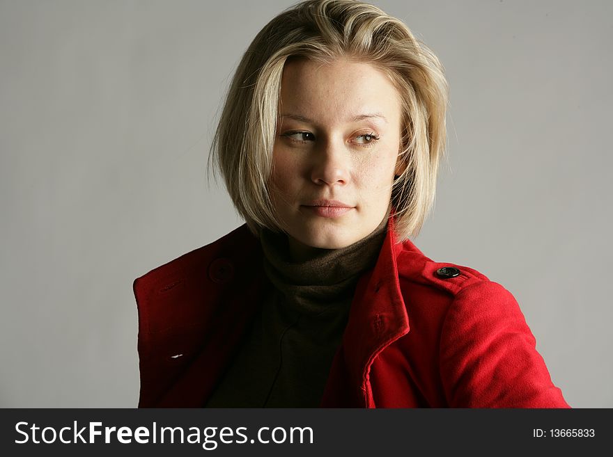 The beautiful young girl-blonde dressed in a brown dress and a red coat. The beautiful young girl-blonde dressed in a brown dress and a red coat.