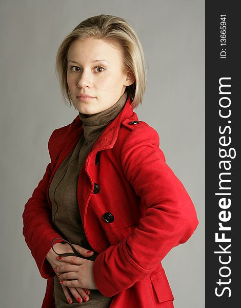 The beautiful young girl-blonde dressed in a brown dress and a red coat. The beautiful young girl-blonde dressed in a brown dress and a red coat.