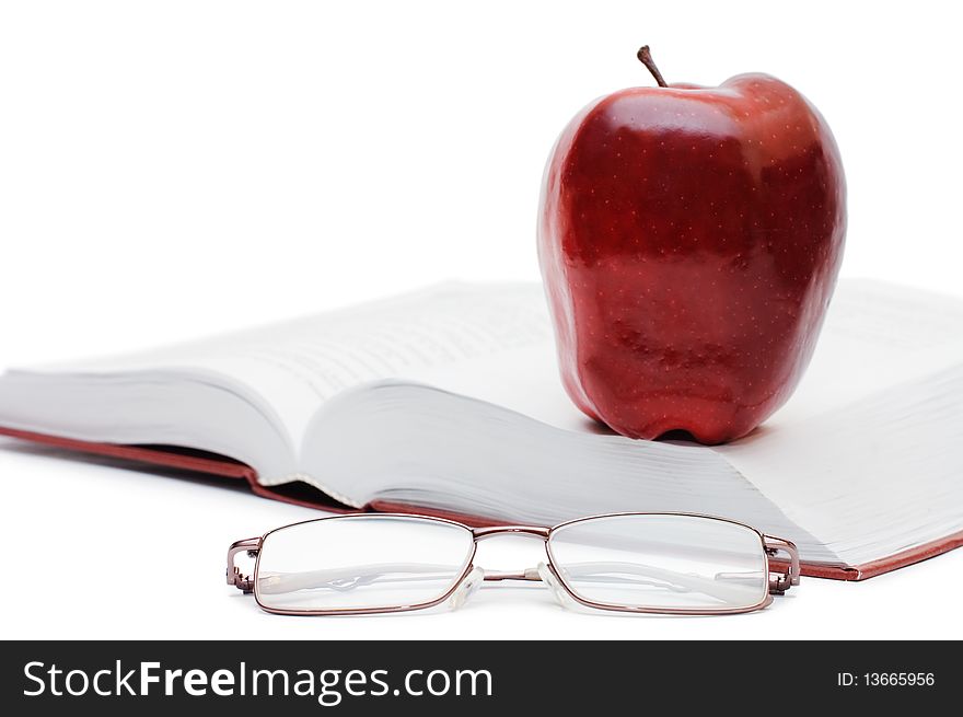 Red apple and glasses on the book isolated over white