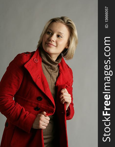 The beautiful young girl-blonde dressed in a brown dress and a red coat. The beautiful young girl-blonde dressed in a brown dress and a red coat.