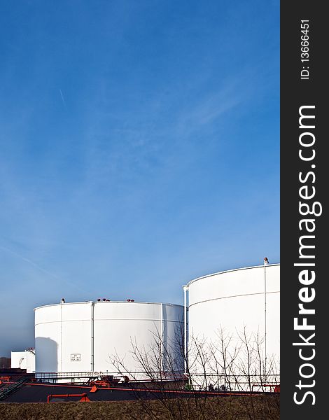 White tanks in tankfarm with staircase to enter the construction with blue sky, storage of petrol, oil. White tanks in tankfarm with staircase to enter the construction with blue sky, storage of petrol, oil