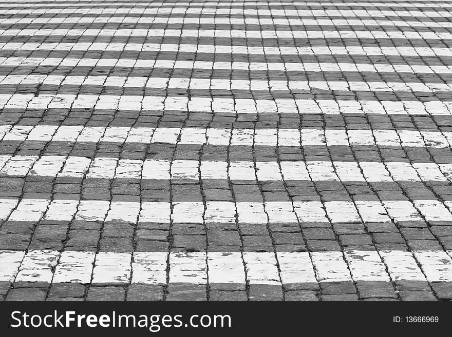 The pedestrian crossing on a pavement. Black and white.