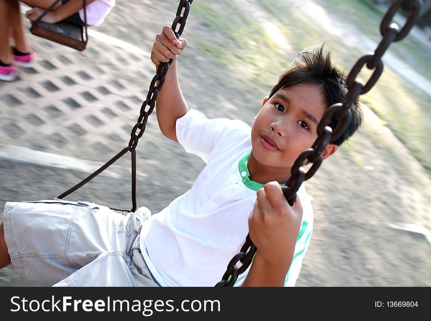 Asian kid enjoying a swing ride. Asian kid enjoying a swing ride