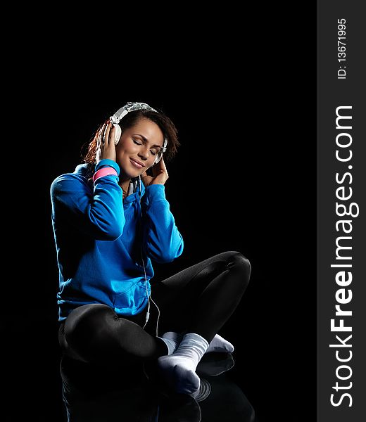 Young woman listening to music on a black background