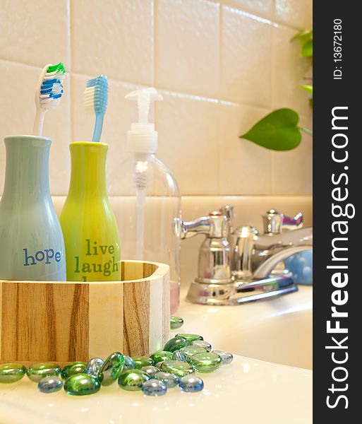 Inspiration word bottles holding toothbrushes with colorful beads for a bathroom sink presentation. Inspiration word bottles holding toothbrushes with colorful beads for a bathroom sink presentation.