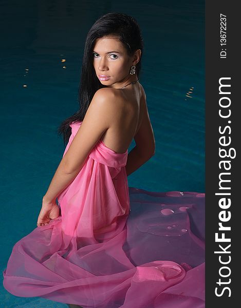 The girl in a pink fabric costs in pool and looks directly. The girl in a pink fabric costs in pool and looks directly.