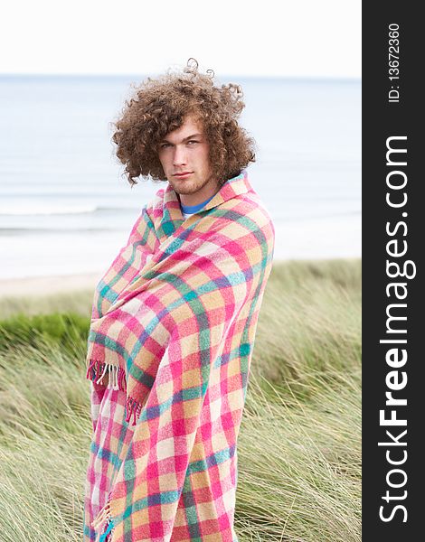 Young Man Standing In Sand Dunes Wrapped In Blanket