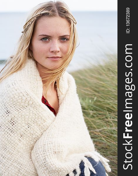 Young Woman Standing In Sand Dunes Wrapped In Blanket