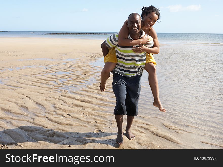 Young Man Giving Woman Piggyback Along Shoreline