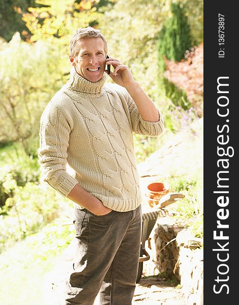 Man Outdoors On Mobile Phone Whilst On Break From Gardening. Man Outdoors On Mobile Phone Whilst On Break From Gardening