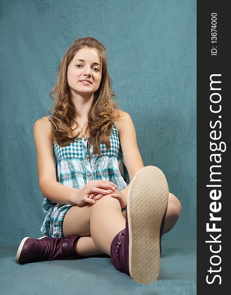 Teenager girl in dress sitting on grey background. Teenager girl in dress sitting on grey background