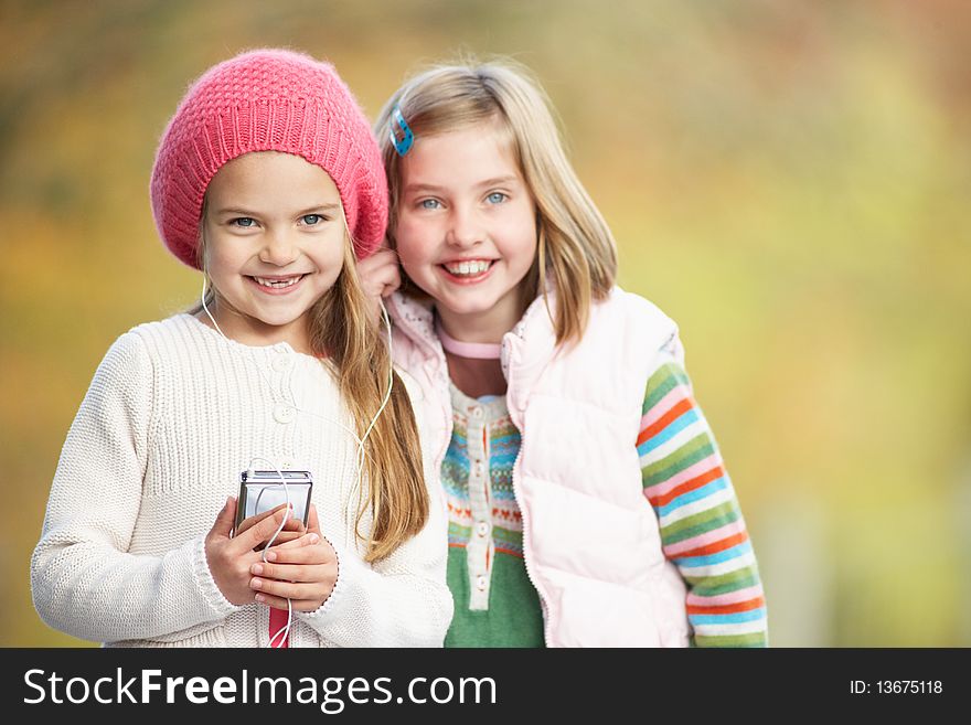 Two Young Girl Outdoors With MP3 Player Smiling At Camera