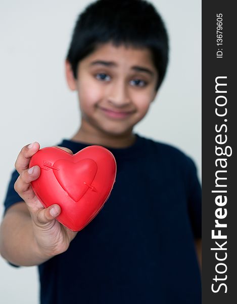 An handsome Indian kid holding out a red heart. An handsome Indian kid holding out a red heart