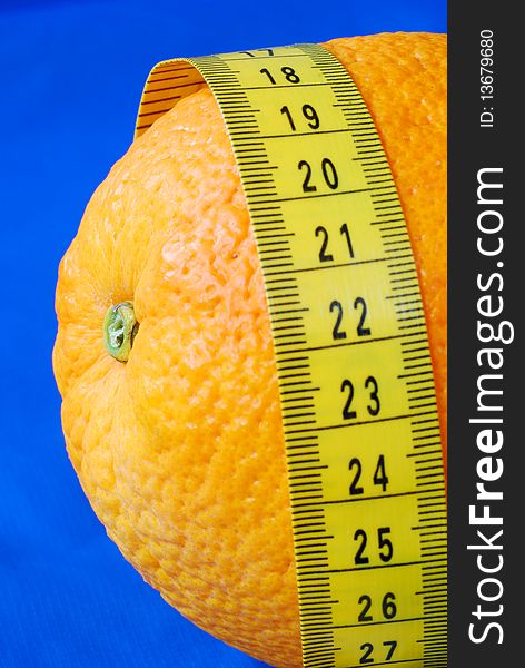 An orange and a measuring tape isolated on blue concepts of healthy diet